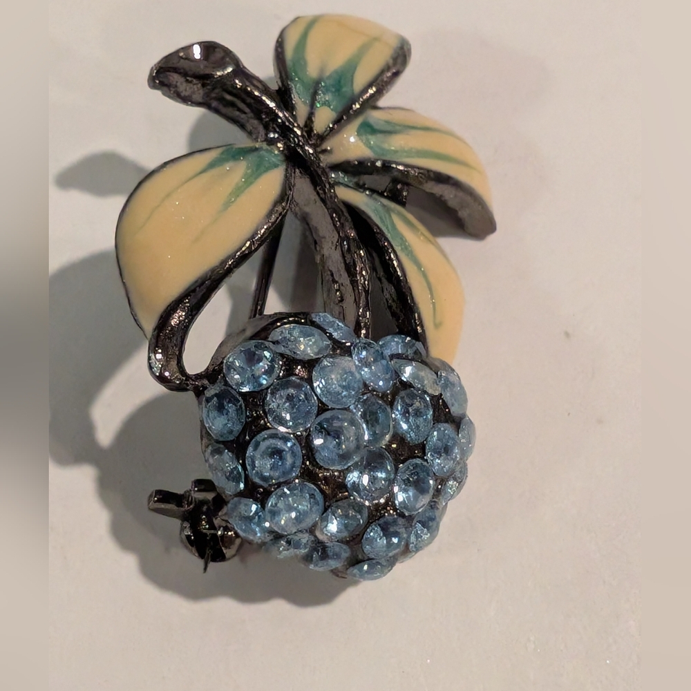 A vintage Hollycraft blue rhinestone with enamel leaves brooch.